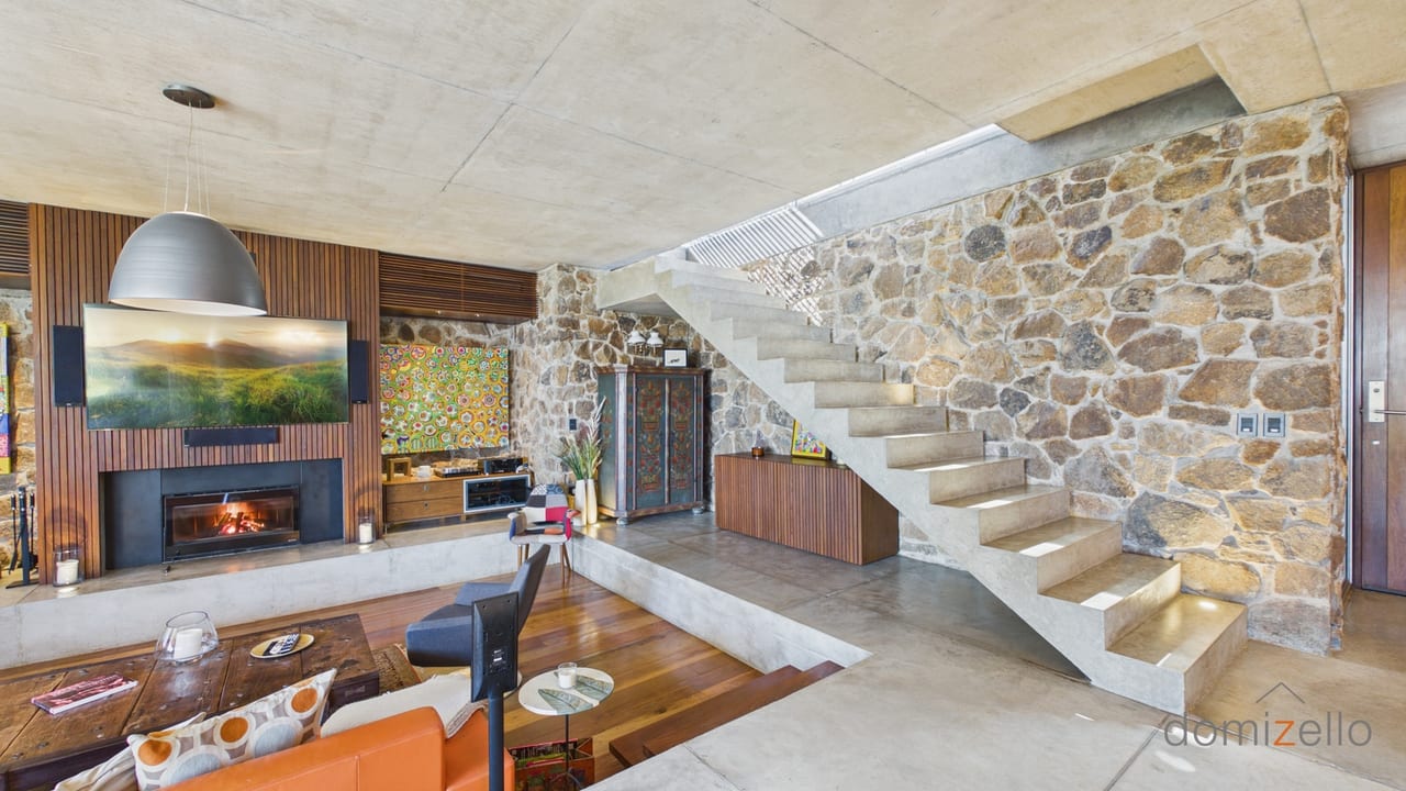 Living room with wood-burning fireplace, concrete stairs and stone wall, house in El Quijote, Maldonado
