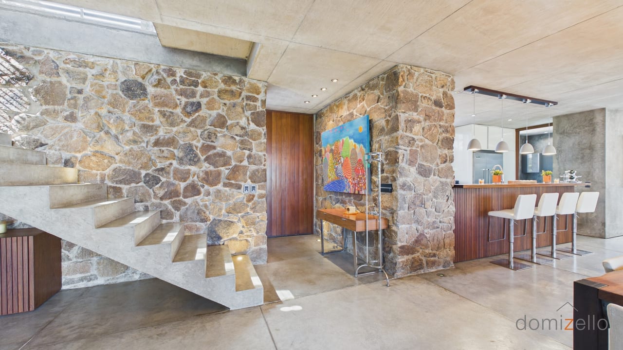 Living dining area with concrete staircase and stone walls, house in El Quijote, Maldonado