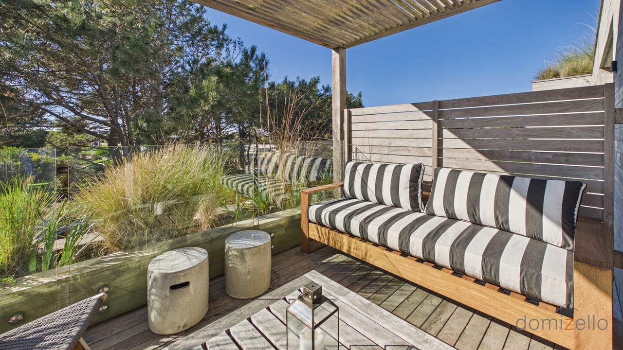 Terraza con pergolado, sofá integrado y vista a jardín con árboles, apartamento en Faro de José Ignacio, Maldonado