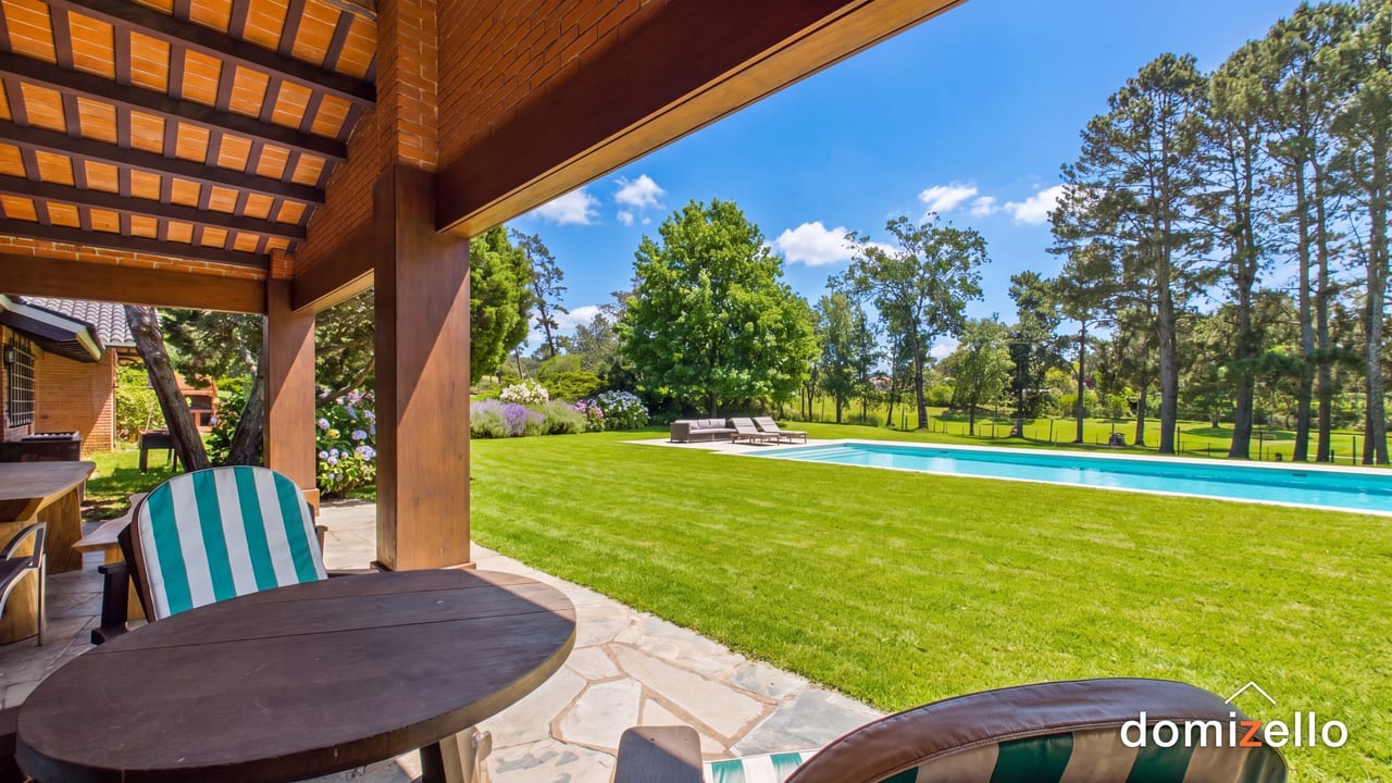 Terraza cubierta con techo de madera, vista a la piscina y al jardín, casa en Punta del Este, Maldonado
