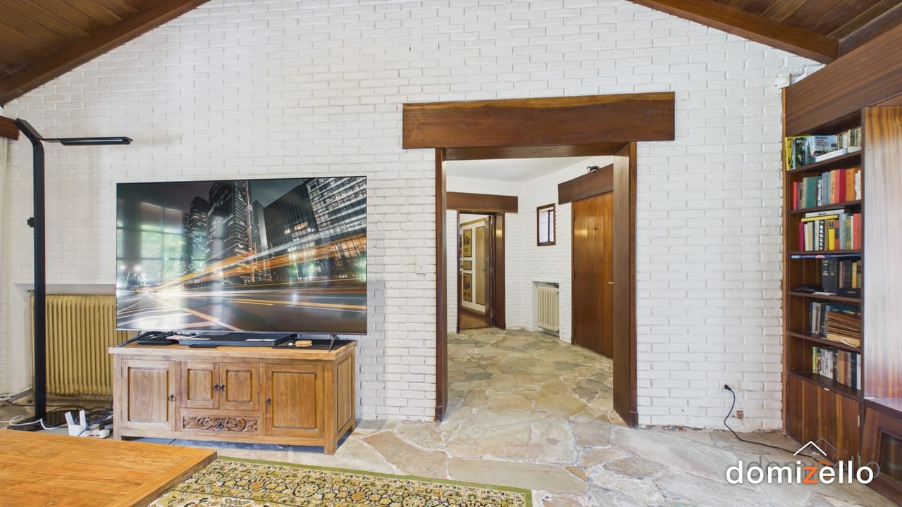 Living con paredes de ladrillo pintado, piso de piedra y techo de madera, casa en Punta del Este, Maldonado