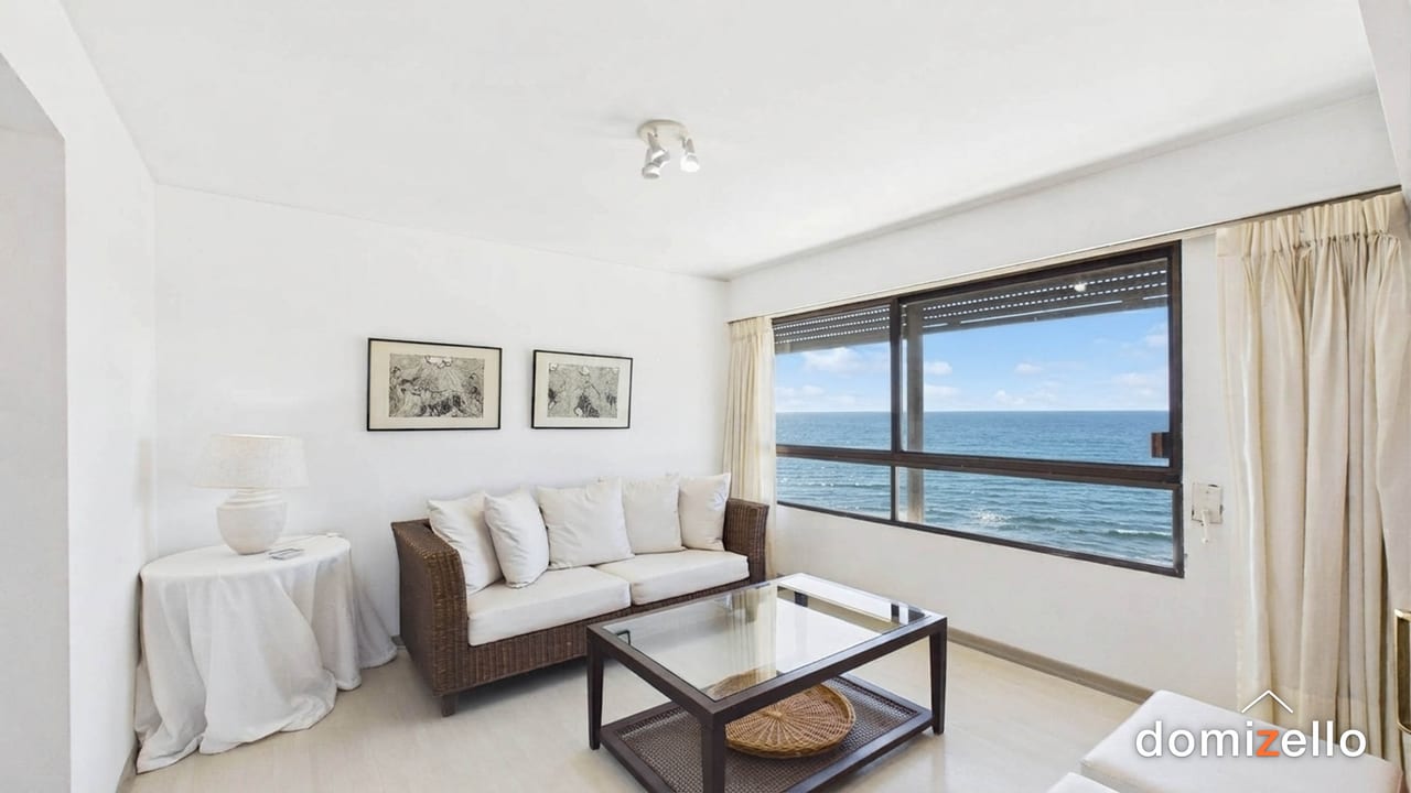 Living con sofá de mimbre, ventanal con vista al mar y cortinas claras, apartamento en Península, Punta del Este